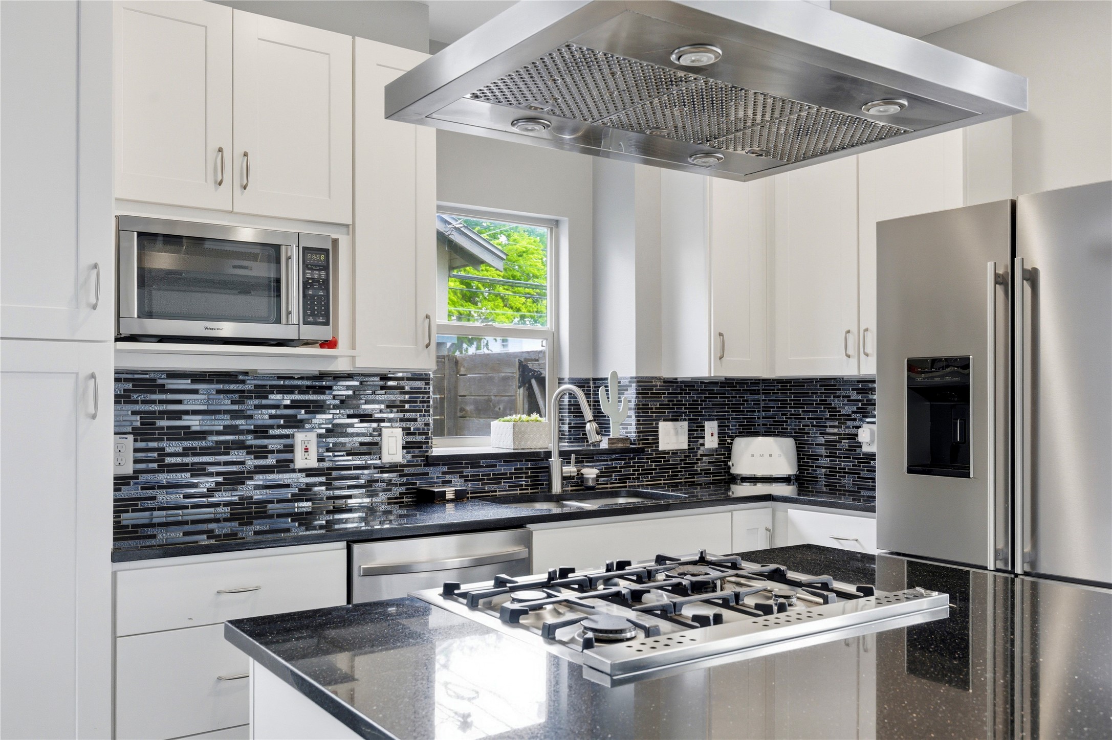 2202 Willow Street, Unit B Austin, TX 78702 - Photo 6 of 21 Kitchen featuring stainless steel appliances, dark stone countertops, white cabinetry, decorative backsplash, and a center island