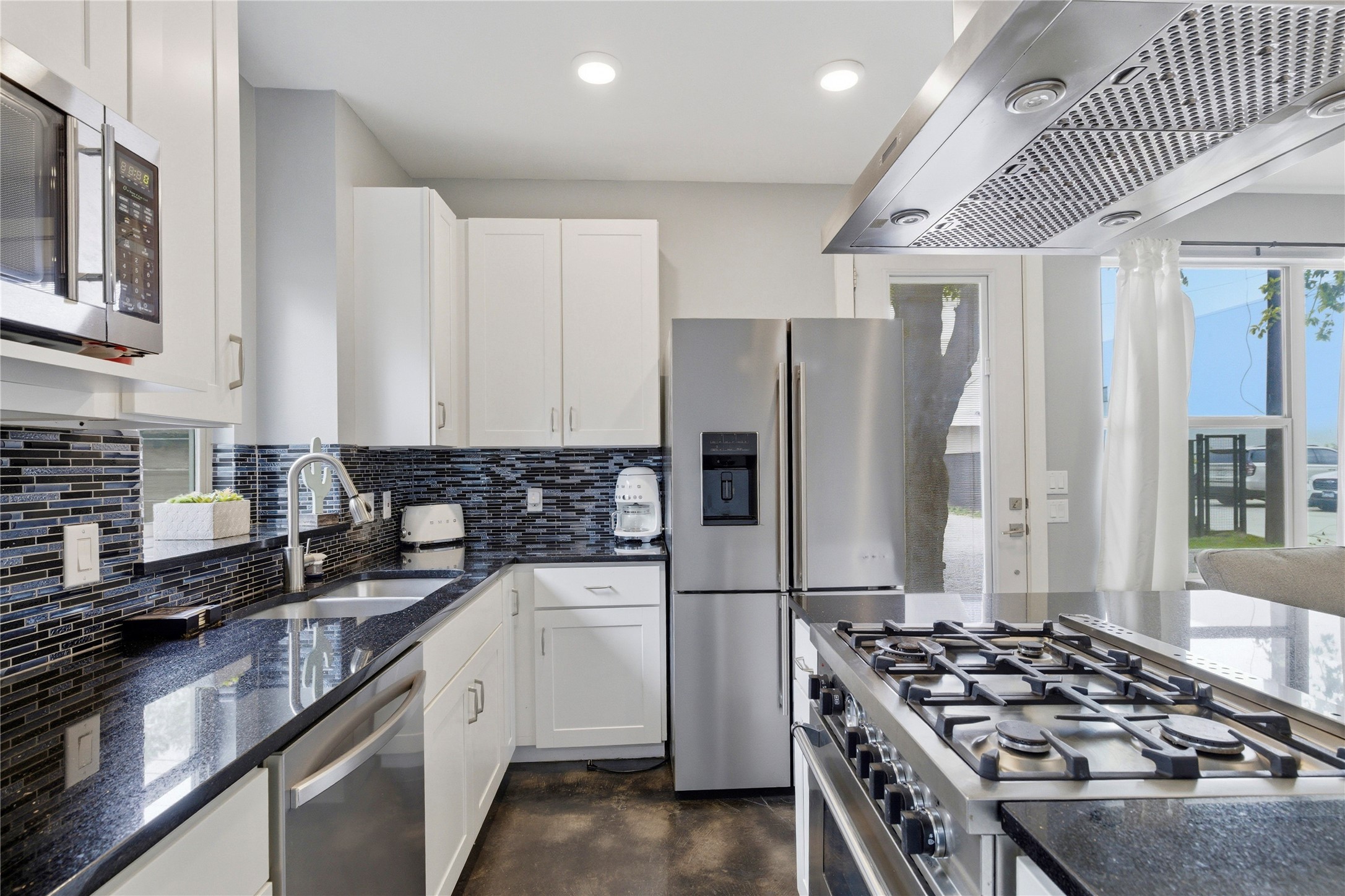 2202 Willow Street, Unit B Austin, TX 78702 - Photo 7 of 21 Kitchen with stainless steel appliances, range hood, dark stone countertops, finished concrete floors, and white cabinetry