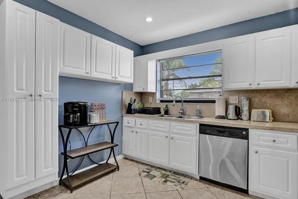 a kitchen with white cabinets and sink