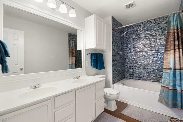 a bathroom with a bathtub sink mirror vanity and toilet