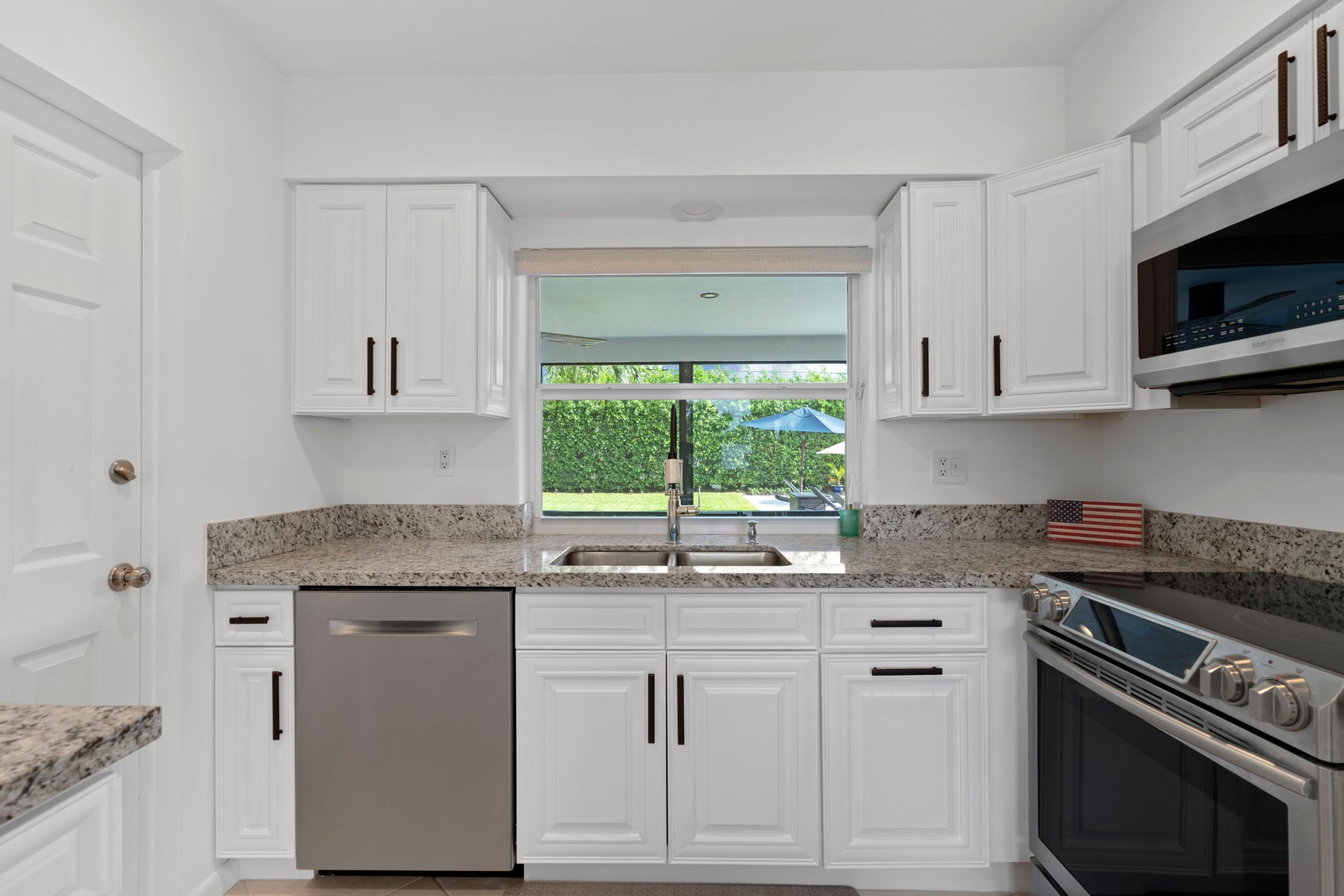 1093 Southwest 14th Street Boca Raton, FL 33486 - Photo 7 of 18 a kitchen with granite countertop a sink cabinets stainless steel appliances and a window