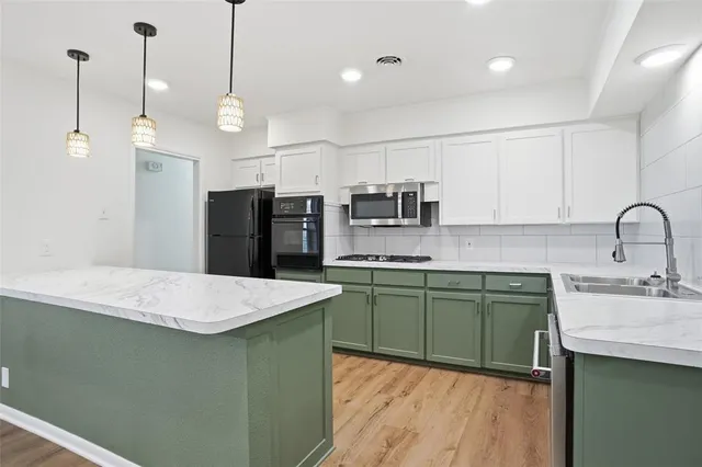 a kitchen with stainless steel appliances granite countertop a sink a stove a refrigerator and island