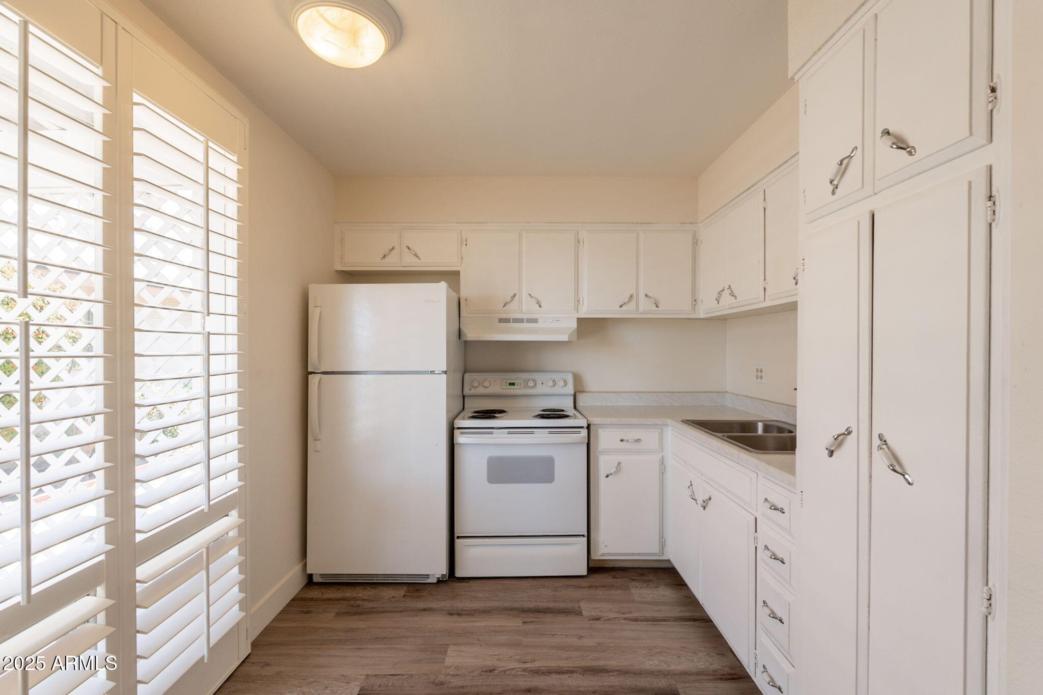 13001 North 113th Avenue, Unit 5 Youngtown, AZ 85363 - Photo 12 of 36 a kitchen with white cabinets and white appliances