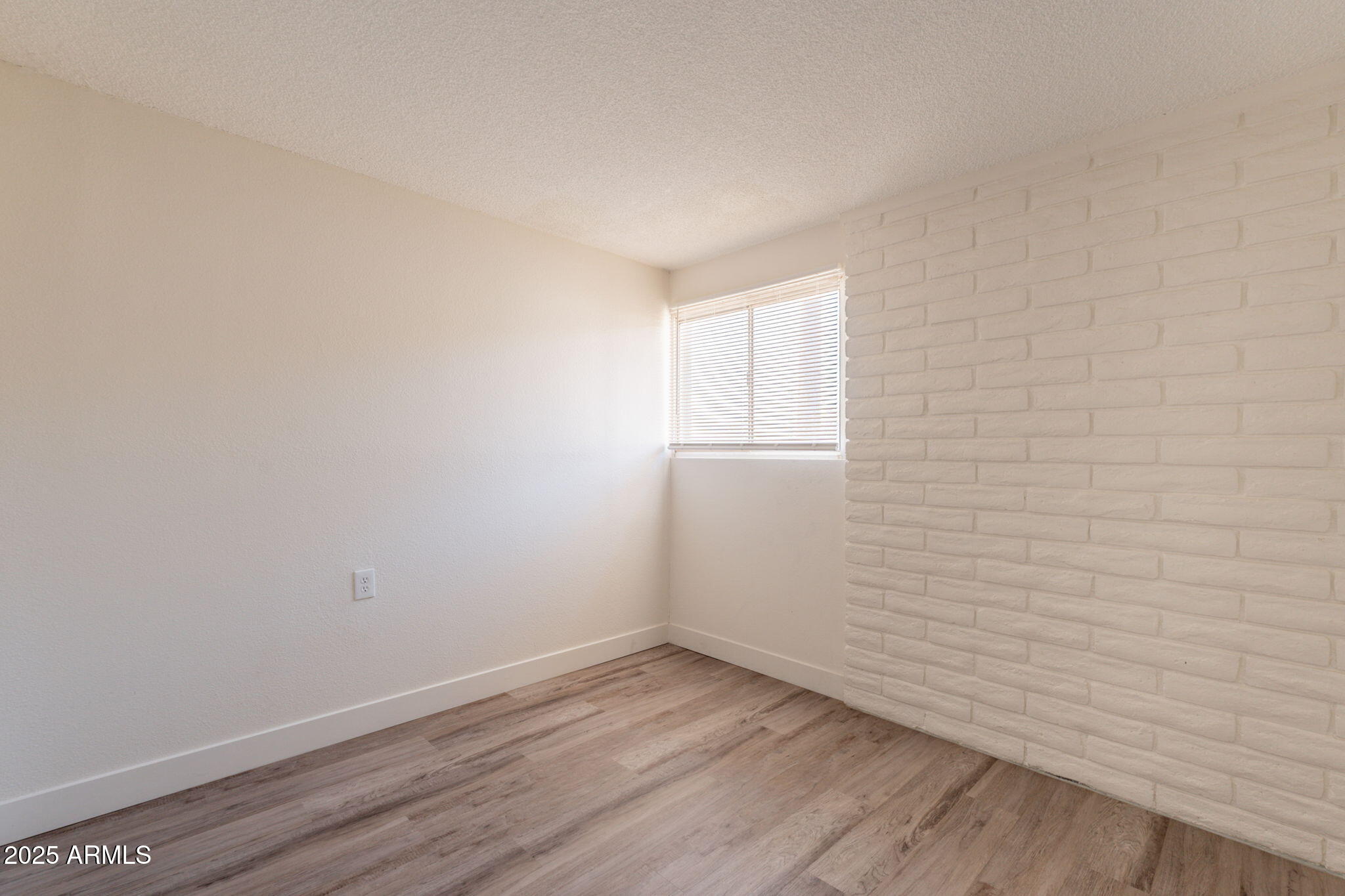 13001 North 113th Avenue, Unit 5 Youngtown, AZ 85363 - Photo 22 of 36 a view of an empty room with wooden floor and a window