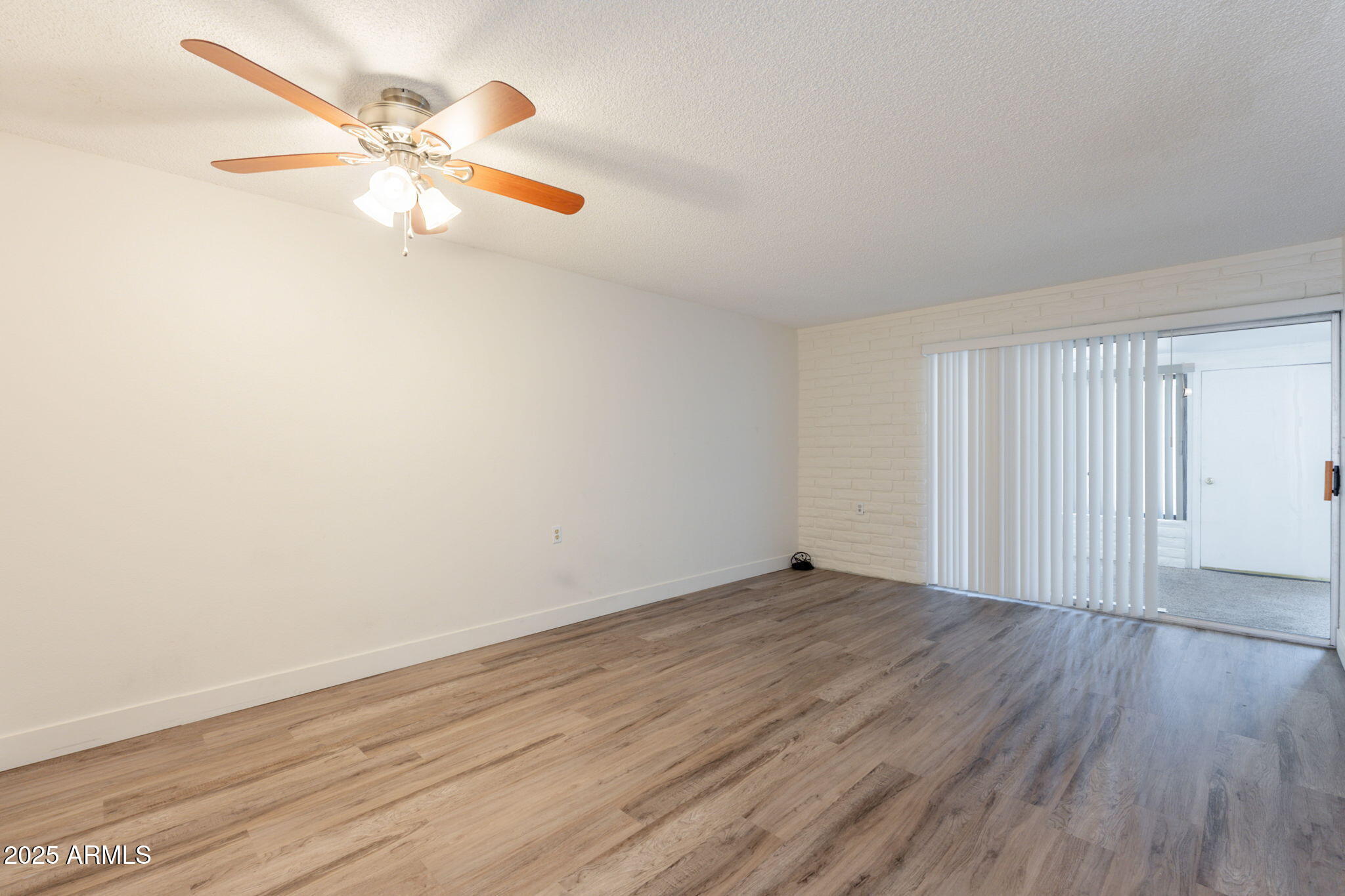 13001 North 113th Avenue, Unit 5 Youngtown, AZ 85363 - Photo 4 of 36 an empty room with wooden floor fan and windows
