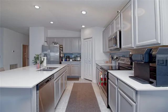 a kitchen with kitchen island granite countertop a sink a counter top space stainless steel appliances and cabinets