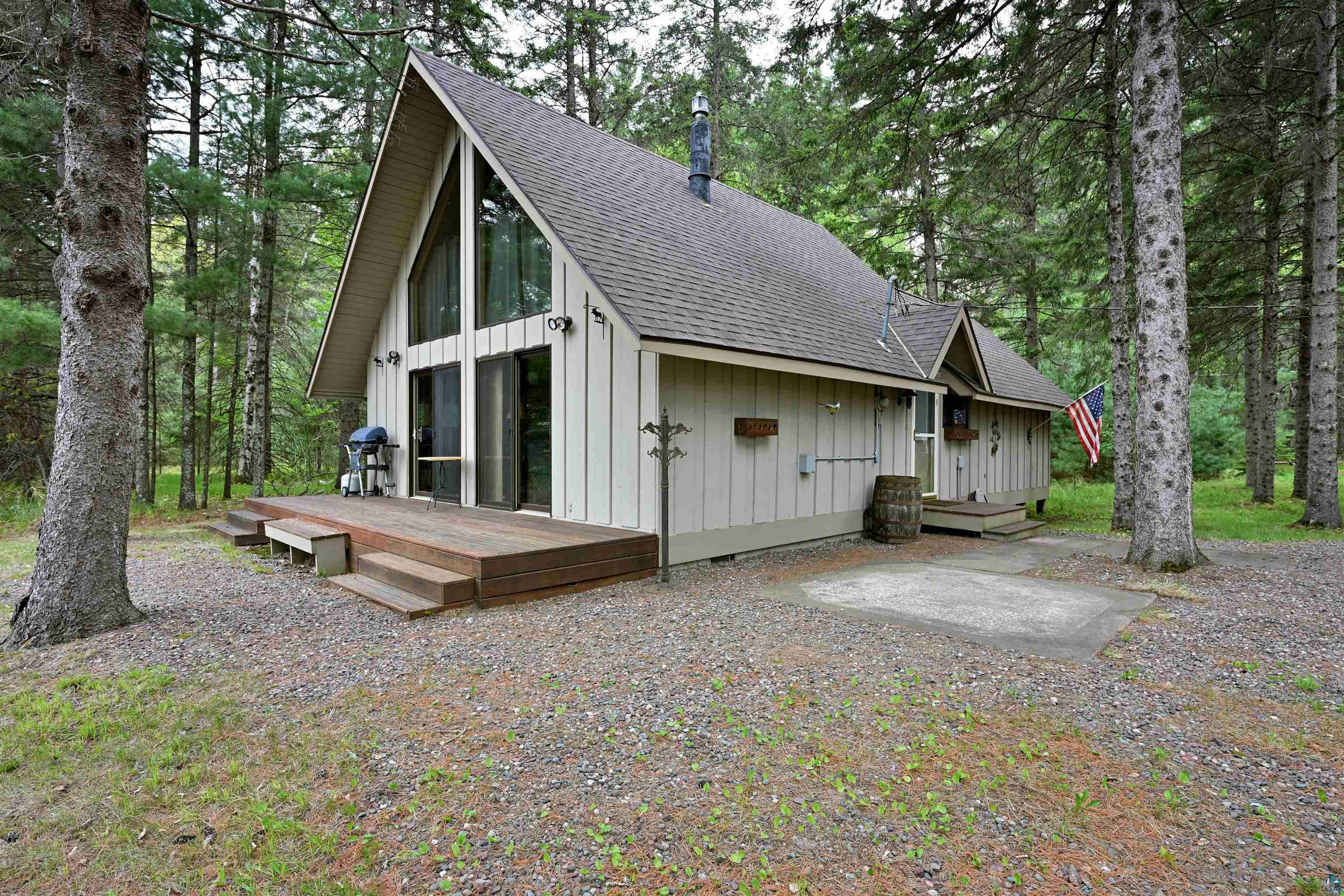 2775 Lake Road Barnes, WI 54873 - Photo 24 of 52 View of home's exterior featuring roof with shingles, board and batten siding, a deck, and view of wooded area