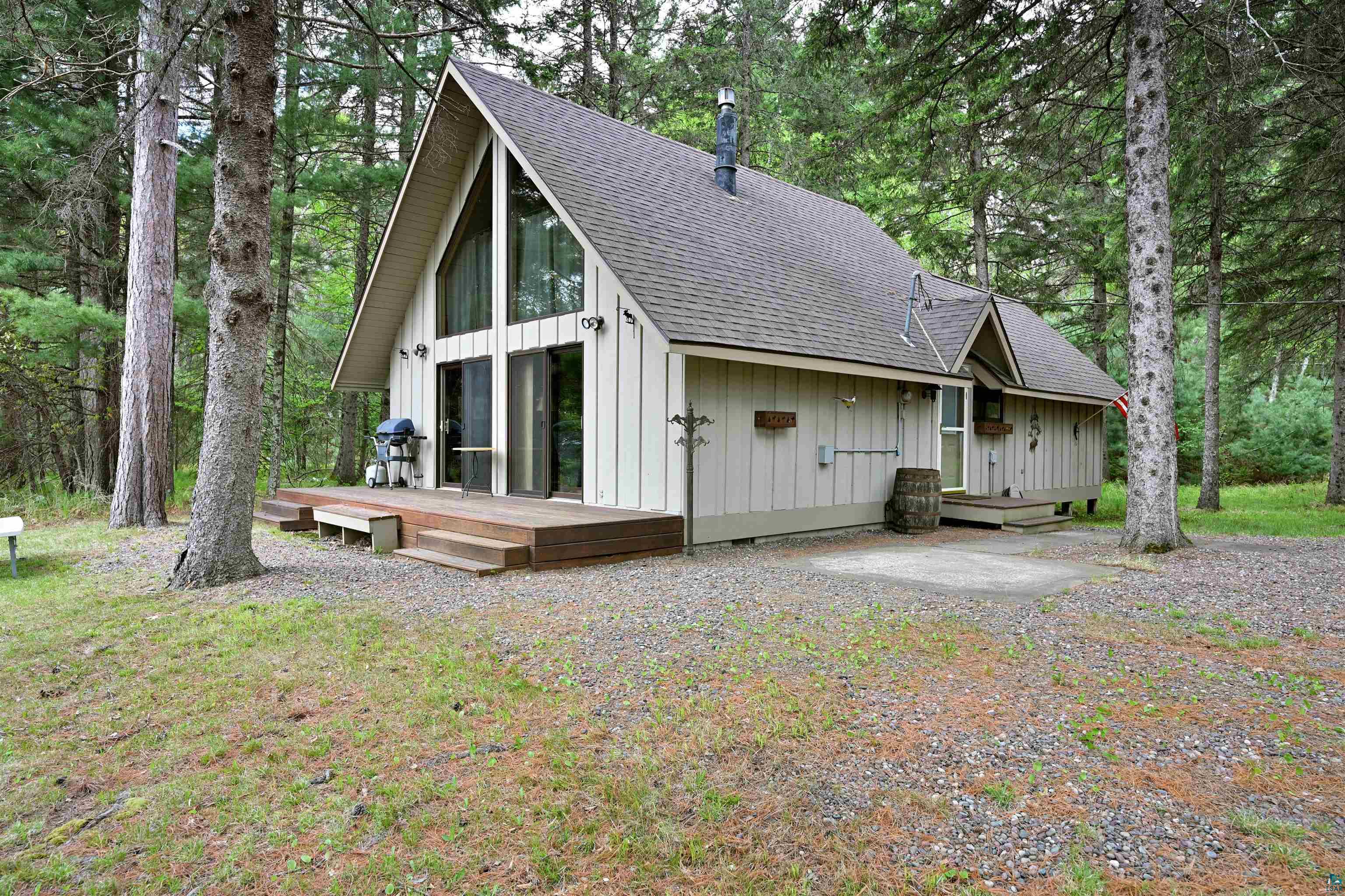 2775 Lake Road Barnes, WI 54873 - Photo 35 of 52 Back of property featuring a shingled roof, board and batten siding, a wooden deck, and view of scattered trees