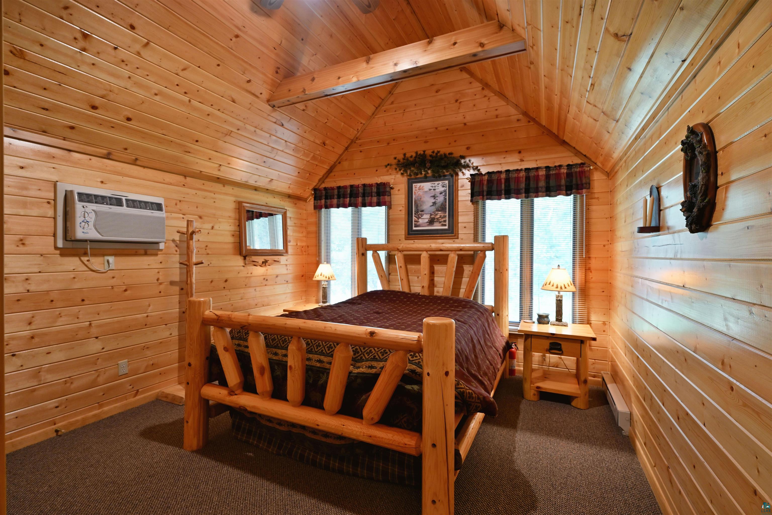2775 Lake Road Barnes, WI 54873 - Photo 36 of 52 Bedroom featuring dark carpet, wooden walls, wooden ceiling, vaulted ceiling with beams, and a baseboard radiator