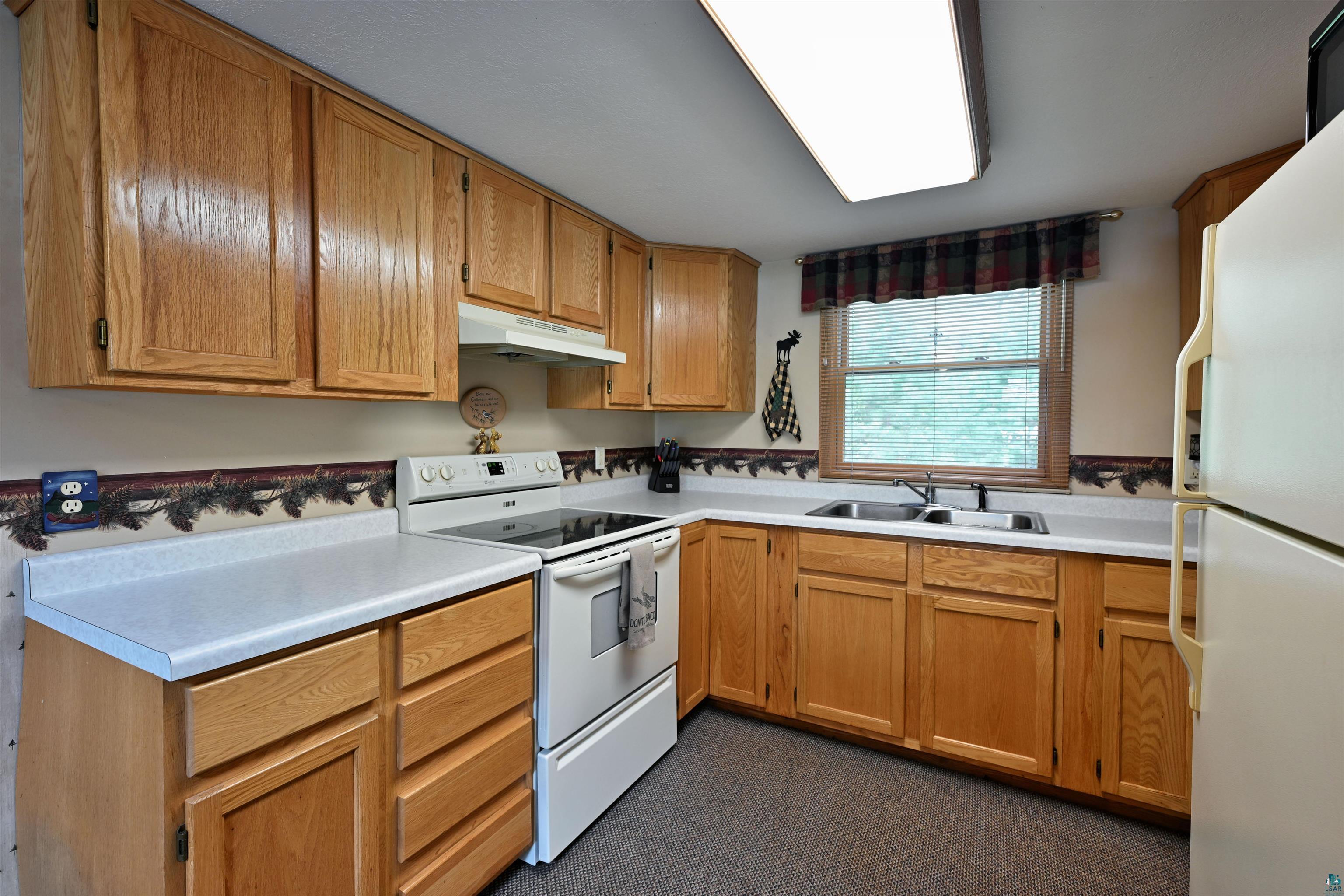 2775 Lake Road Barnes, WI 54873 - Photo 37 of 52 Kitchen featuring white appliances, light countertops, and wood finish cabinetry
