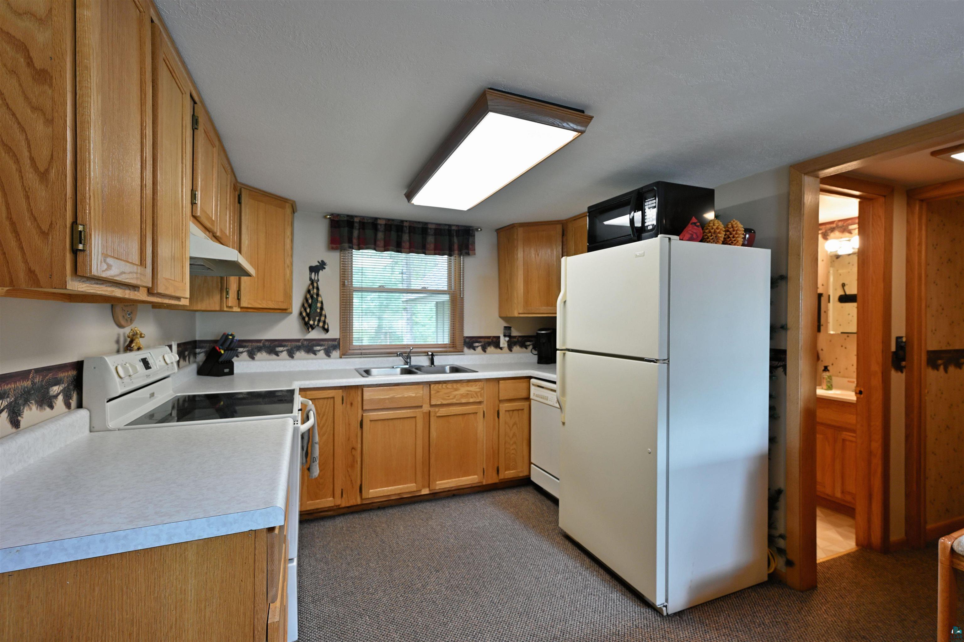 2775 Lake Road Barnes, WI 54873 - Photo 38 of 52 Kitchen with white appliances, light countertops, and wood finish cabinets