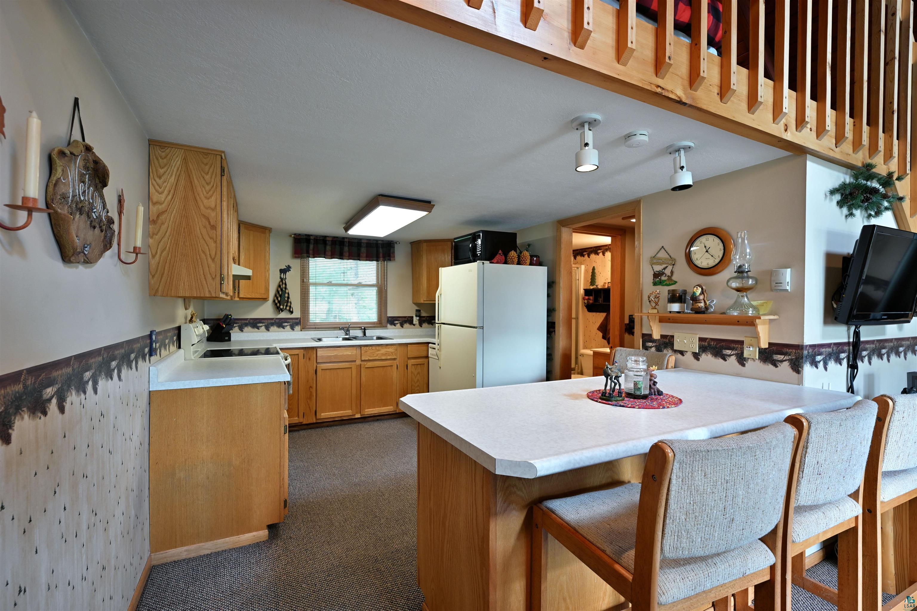 2775 Lake Road Barnes, WI 54873 - Photo 40 of 52 Kitchen with a breakfast bar area, white appliances, light countertops, a peninsula, and wood finish cabinetry