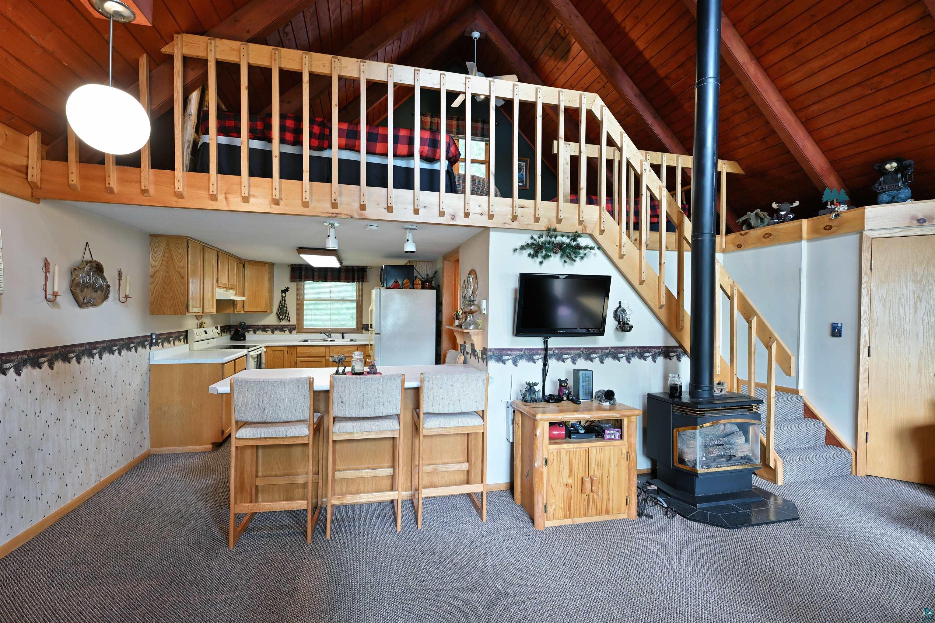 2775 Lake Road Barnes, WI 54873 - Photo 42 of 52 Kitchen featuring a wood stove, light countertops, white appliances, dark carpet, and a high wood beamed ceiling