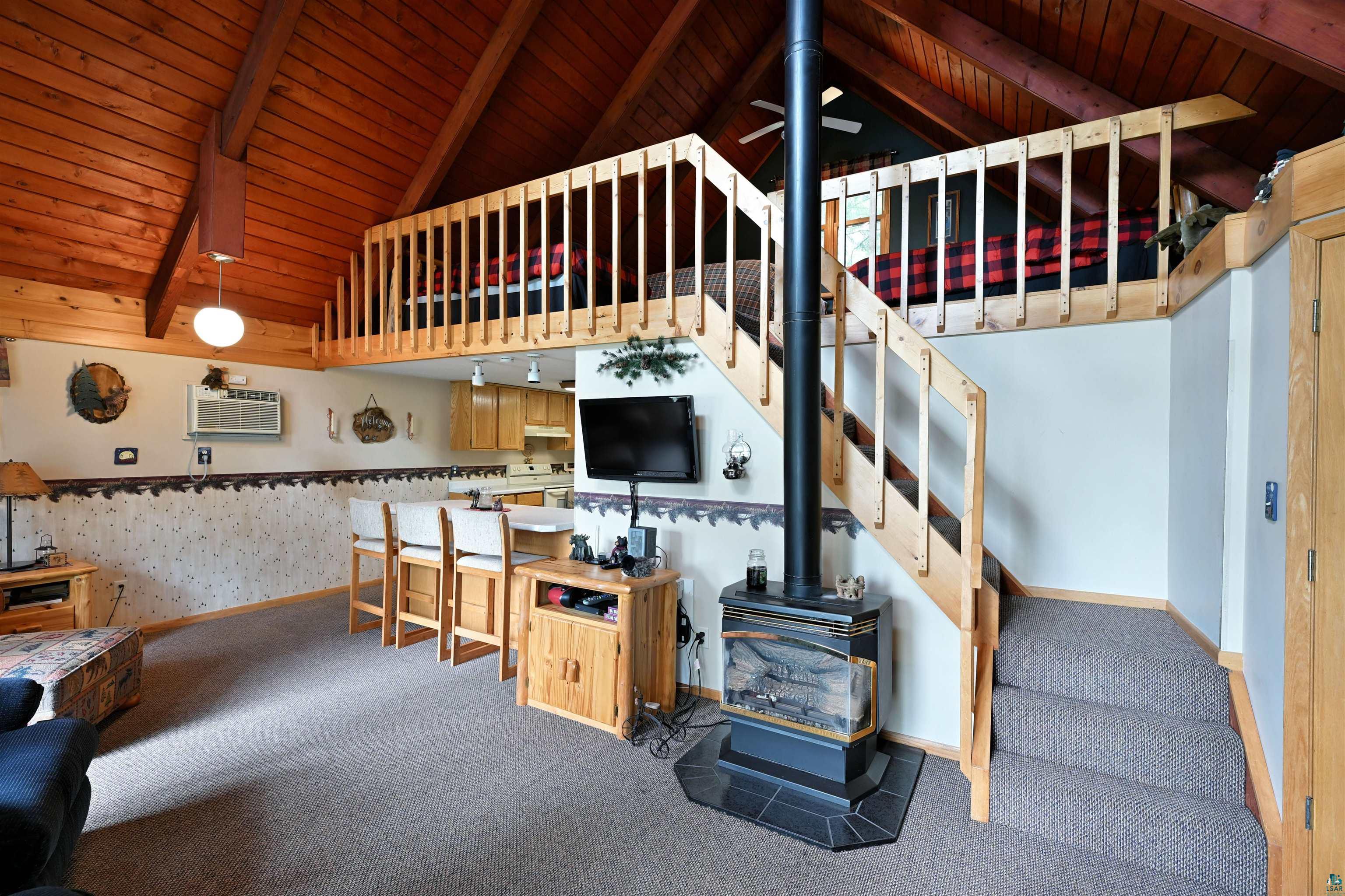 2775 Lake Road Barnes, WI 54873 - Photo 43 of 52 Stairs with a wood stove, carpet flooring, a high wooden beamed ceiling, and a ceiling fan