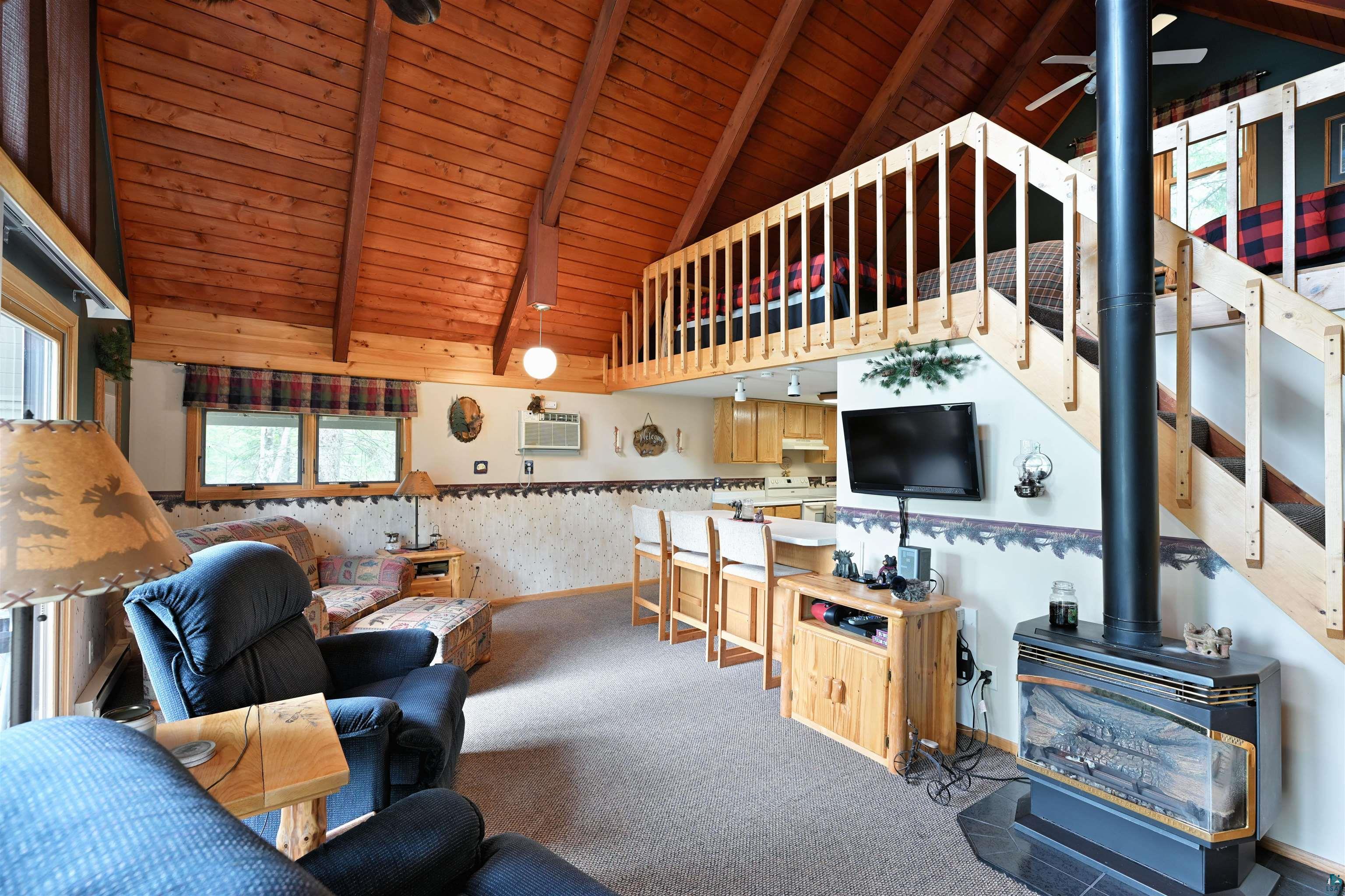 2775 Lake Road Barnes, WI 54873 - Photo 44 of 52 Carpeted living room with a high wooden beamed ceiling, wallpapered walls, a wood stove, and ceiling fan