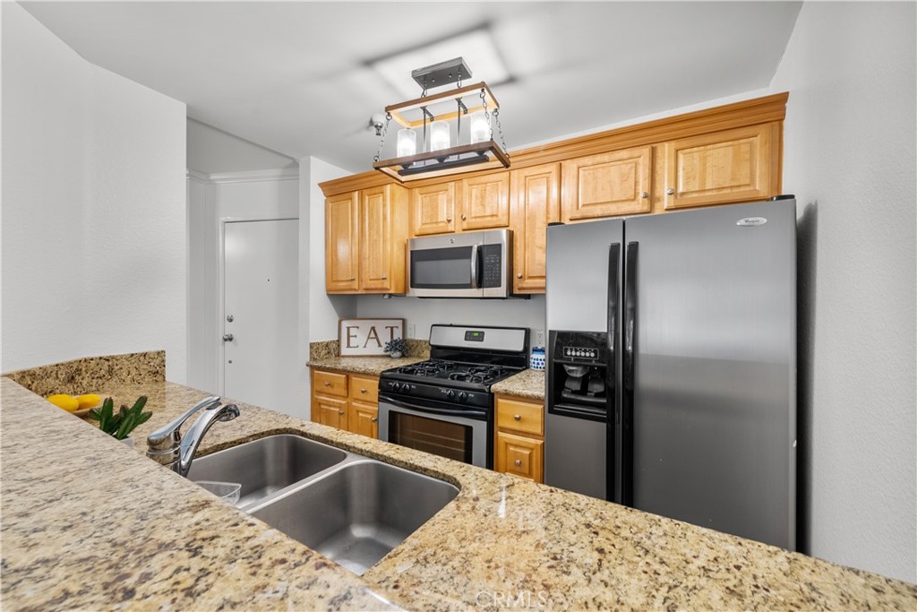 4401 Sepulveda Boulevard, Unit 107 Sherman Oaks, CA 91403 - Photo 7 of 25 a kitchen with granite countertop a sink stainless steel appliances and a refrigerator