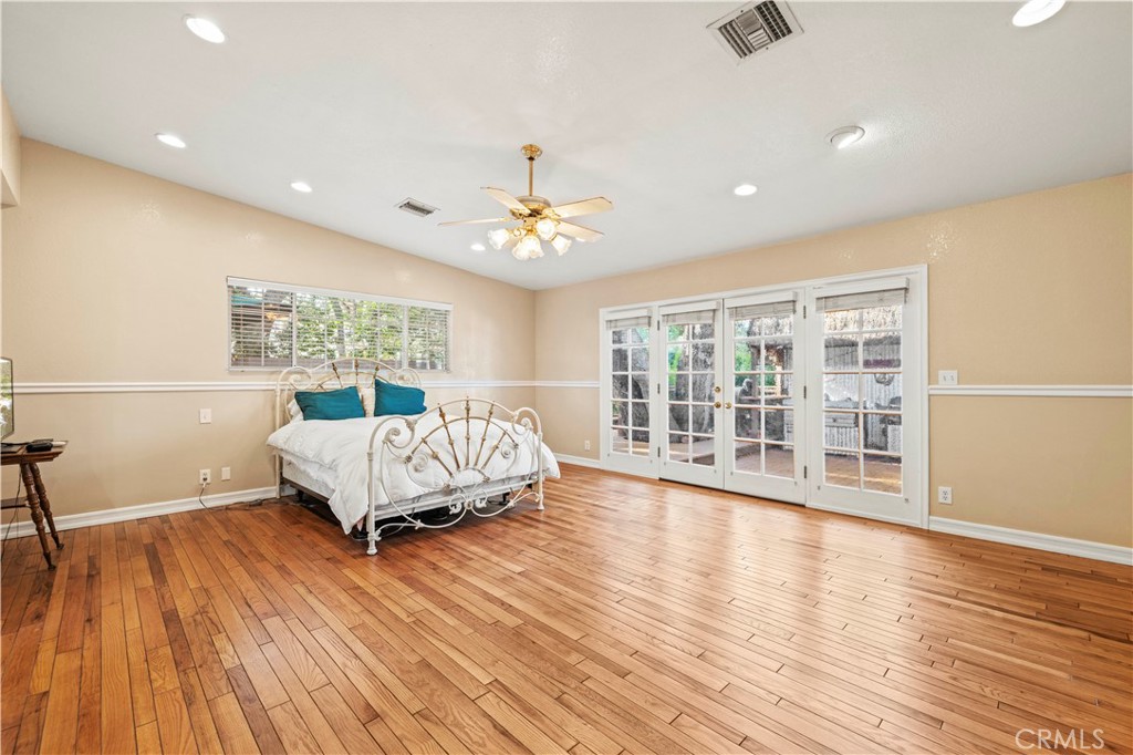 24123 Wildwood Canyon Road Newhall, CA 91321 - Photo 11 of 32 a spacious bedroom with a large bed a chandelier and windows