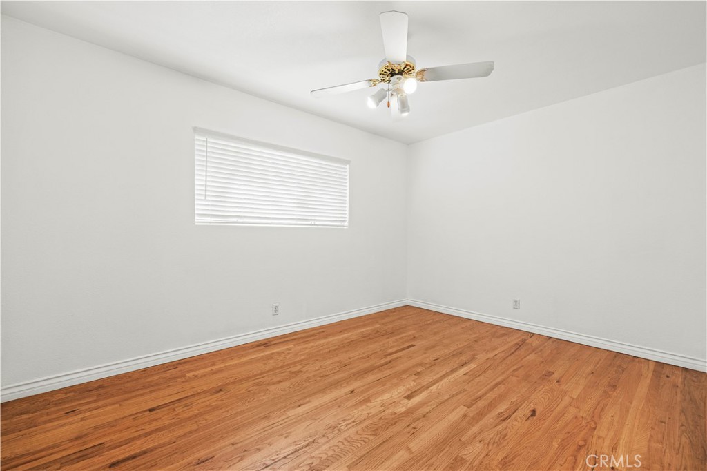 24123 Wildwood Canyon Road Newhall, CA 91321 - Photo 18 of 32 an empty room with wooden floor chandelier fan and windows