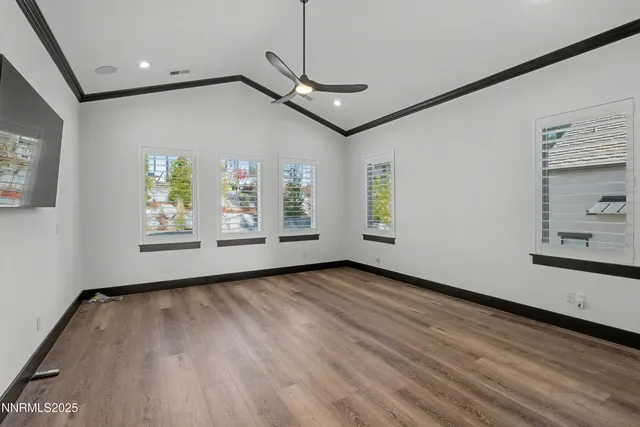 a view of an empty room with window and wooden floor