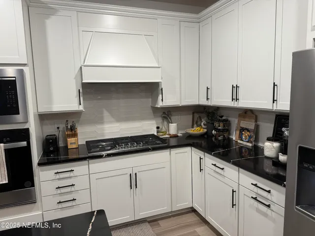 a kitchen with granite countertop white cabinets and white appliances