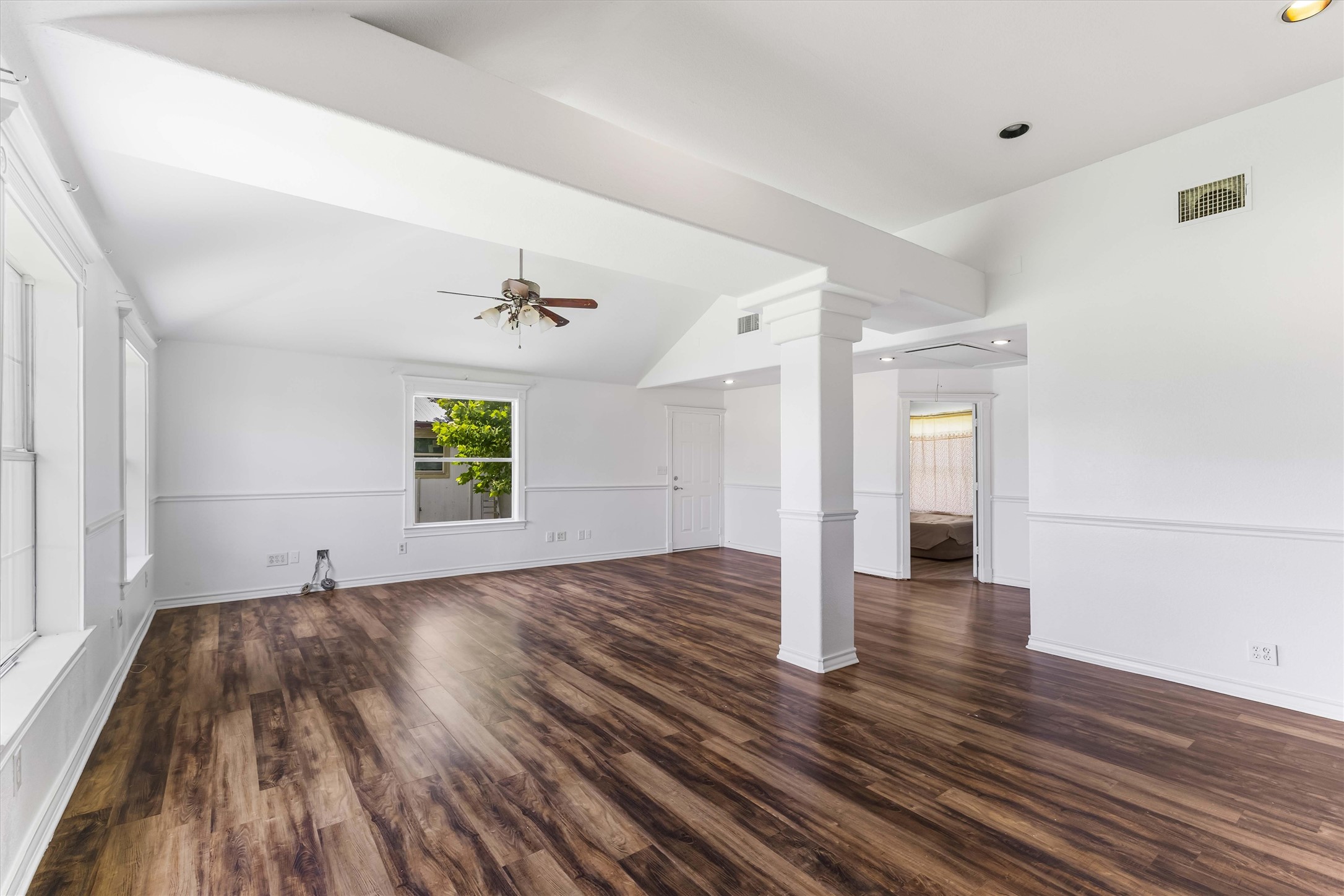 12212 Ballerstedt Road Elgin, TX 78621 - Photo 6 of 39 Unfurnished living room featuring dark wood-type flooring, a ceiling fan, vaulted ceiling, recessed lighting, and ornate columns