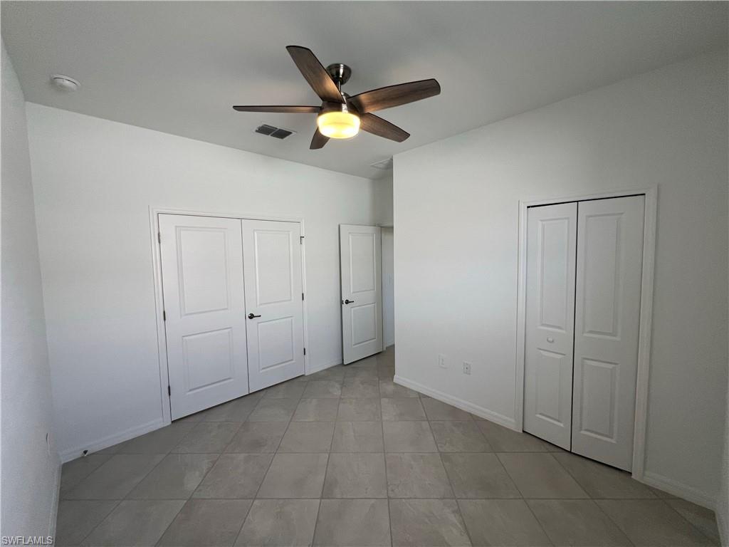 2320 Dragonfruit Way Naples, FL 34120 - Photo 15 of 33 Unfurnished bedroom with light tile patterned floors, baseboards, a ceiling fan, and visible vents