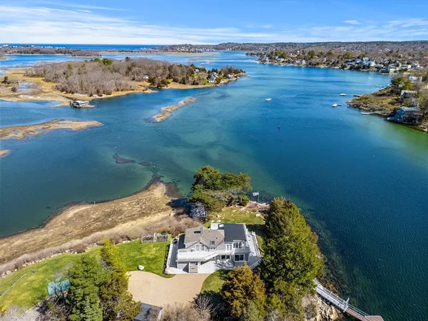 a view of a white house with a small yard plants and large tree