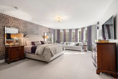 a spacious bedroom with a bed a couch and large window
