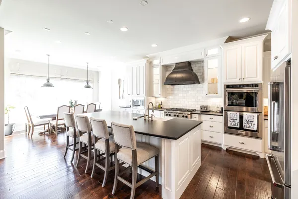 a kitchen with stainless steel appliances a stove a sink a microwave a dining table and chairs with wooden floor