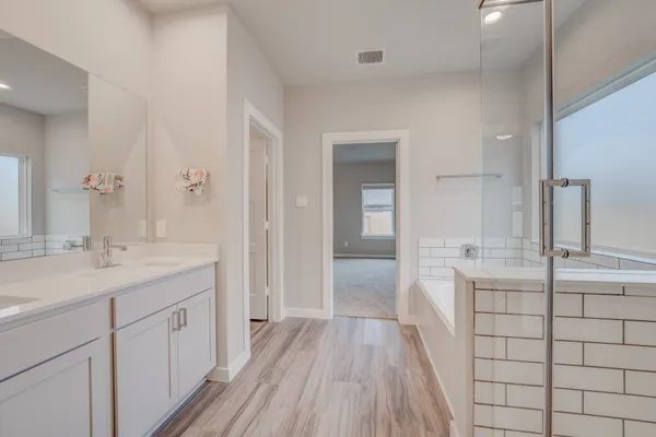 a spacious bathroom with a double vanity sink a mirror and shower