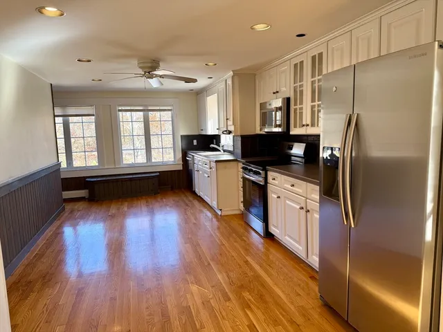 a kitchen with stainless steel appliances a refrigerator a stove top oven and wooden floors