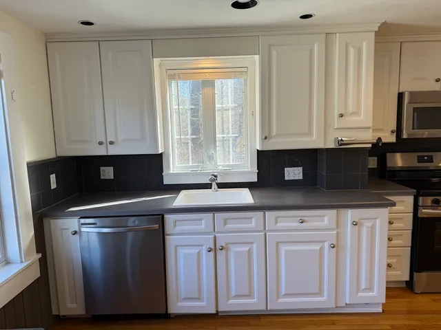 a kitchen with granite countertop white cabinets and sink