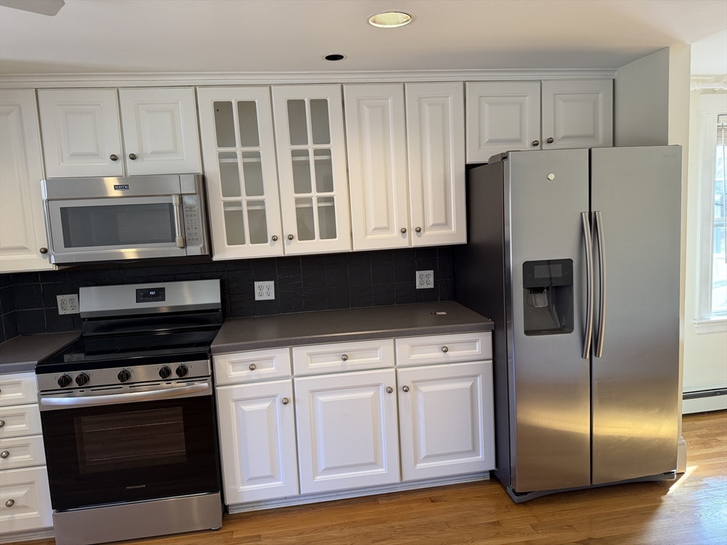 24 State Street, Unit 2 Wellesley, MA 02482 - Photo 6 of 21 a kitchen with stainless steel appliances granite countertop a refrigerator a stove a sink and dishwasher with white cabinets