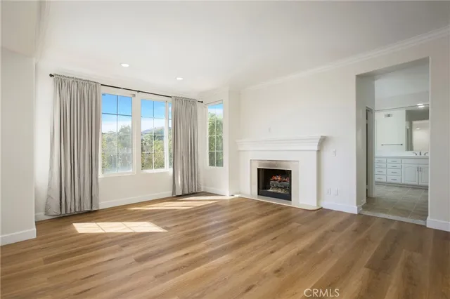 a view of an empty room with wooden floor fireplace and a window