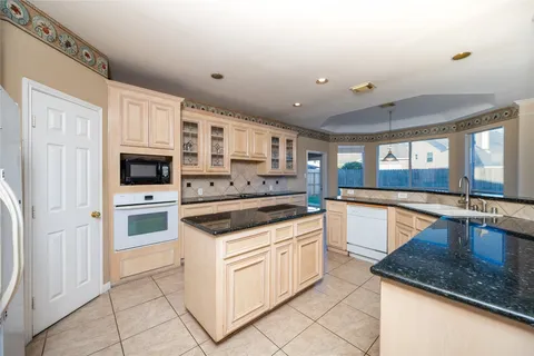a large kitchen with stainless steel appliances granite countertop a sink and cabinets