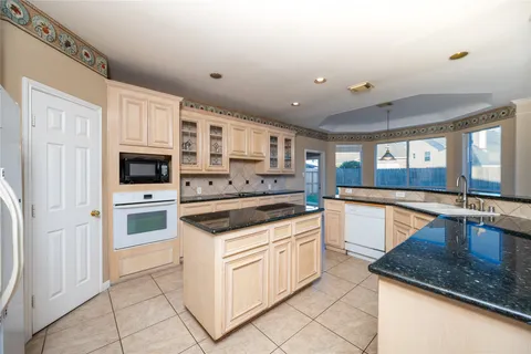 a large kitchen with stainless steel appliances granite countertop a large window and a sink