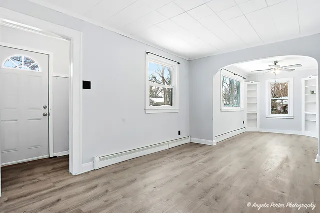 an empty room with wooden floor and windows