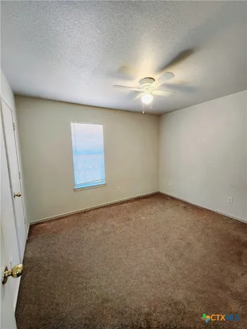 an empty room with a ceiling fan and window
