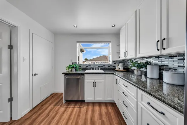 a kitchen with granite countertop a sink stainless steel appliances and cabinets