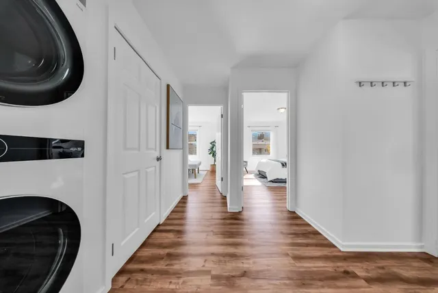 a view of a hallway with wooden floor and a bathroom