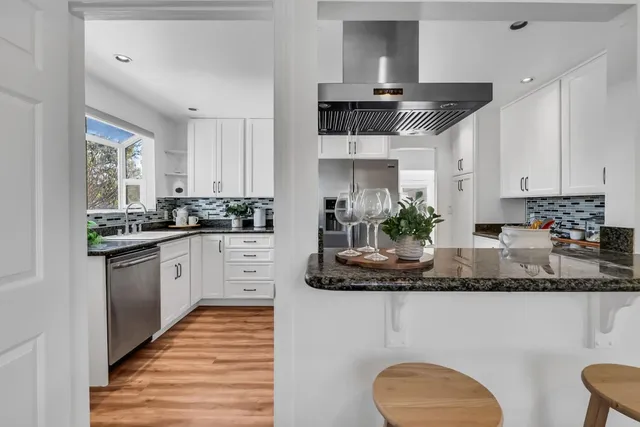 a kitchen with stainless steel appliances granite countertop a white cabinets sink and stove