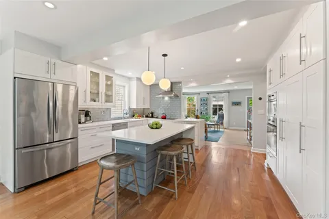 a kitchen with stainless steel appliances a dining table chairs stove refrigerator and wooden floor