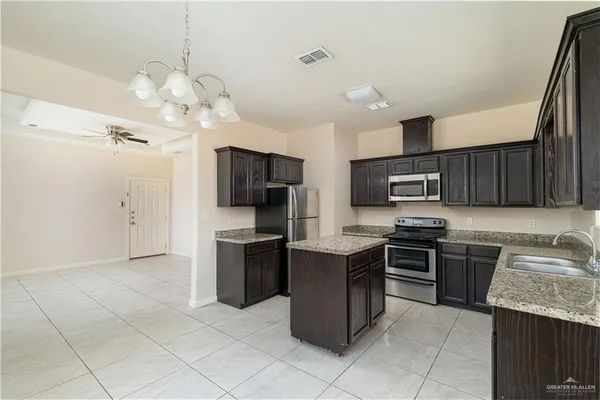 a kitchen with stainless steel appliances granite countertop a sink dishwasher stove top oven and refrigerator