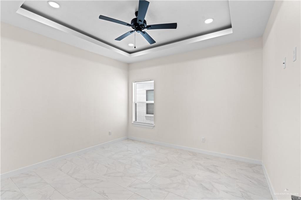503 Sparrow Road Weslaco, TX 78596 - Photo 9 of 14 Spacious room featuring a decorative tray ceiling with recessed lighting and a ceiling fan, a window, and tile flooring