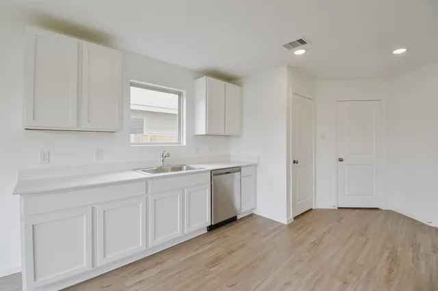 a kitchen with a sink cabinets and wooden floor
