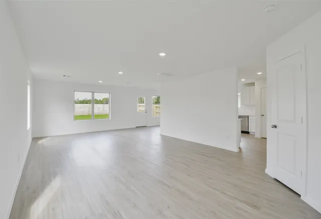 a view of an empty room with a window and wooden floor