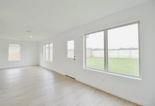 a view of an empty room with a window and wooden floor
