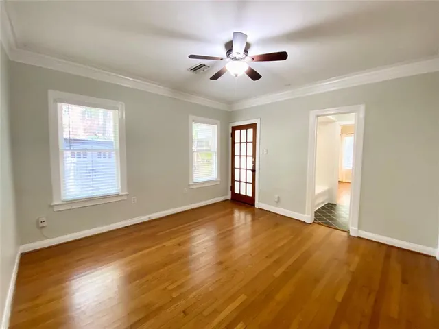 a view of an empty room with chandelier and wooden floor