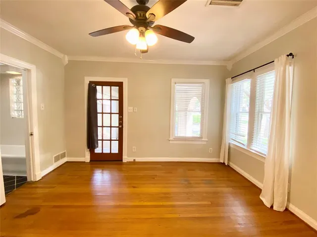 an empty room with wooden floor fan and windows
