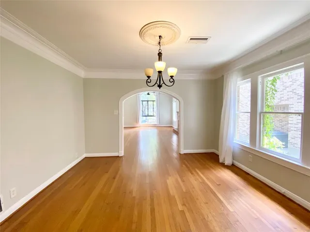 a view of a room with wooden floor chandelier and windows